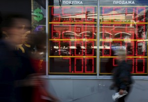 People walk past a board displaying currency exchange rates in Moscow, Russia, June 5, 2015. A slide in the rouble accelerated on June 4 after the Russian central bank said its policy of replenishing forex reserves would continue over several years until the reserves had reached pre-crisis levels. REUTERS/Sergei Karpukhin - RTX1F8ZN
