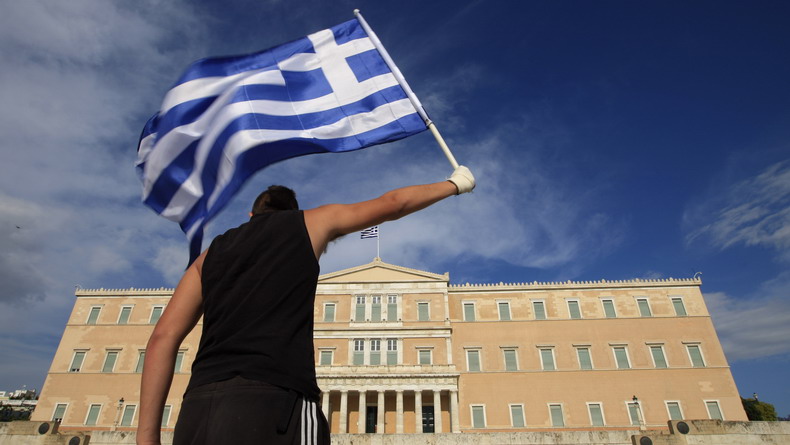 A protester raises Greek flag in front of the parliament during a rally against a new austerity package at Athens' Syntagma square
