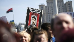 People hold a sign as they attend an anti-war rally at Independence Square in Kiev