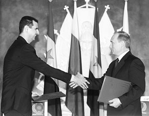 Syrian President al-Assad and Russian President Putin shake hands during the signing ceremony in the ...